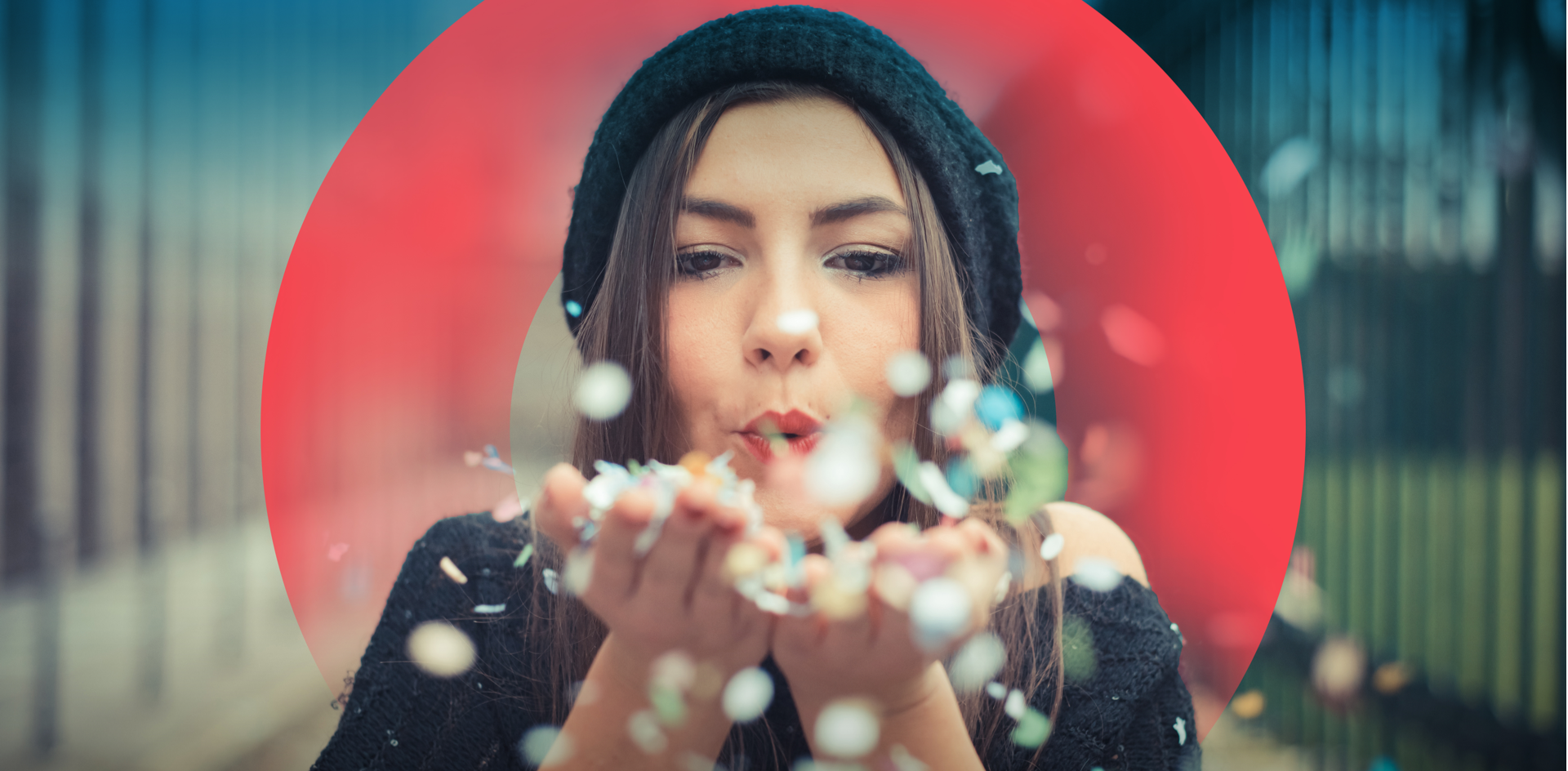 Woman holding out both hands and blowing confetti into the air