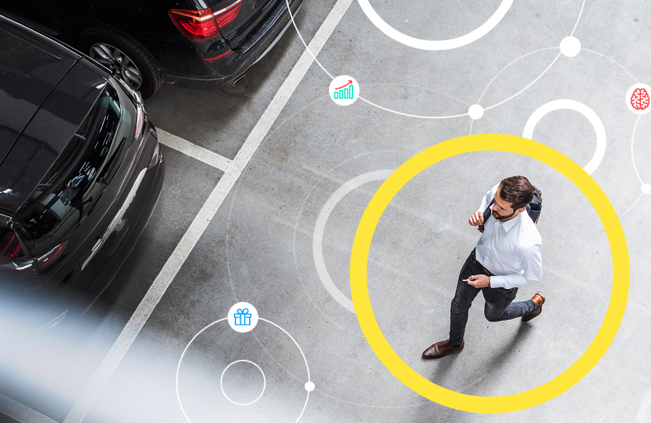 Aerial image of man walking through parking lot to unlock his car